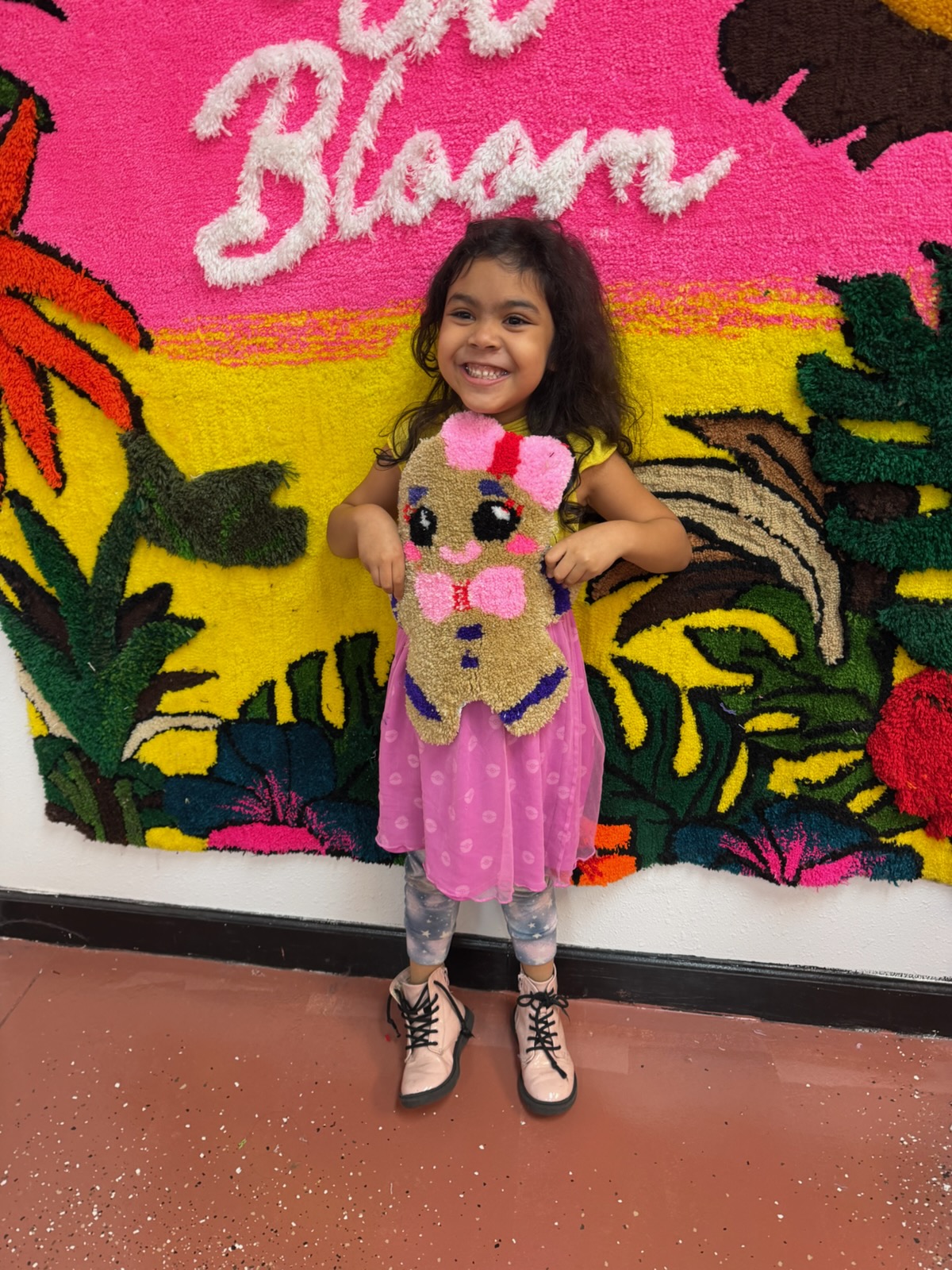 Child holding their finished tufted rug at a kids session